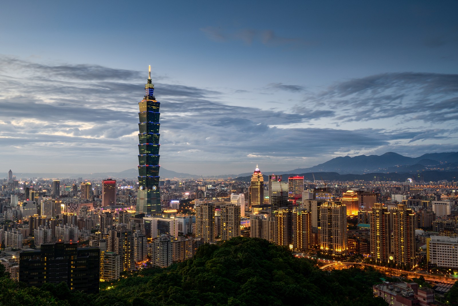 A view of the city skyline at dusk with a tall building in the foreground (taipei 101, cityscape, urban area, city, skyscraper)