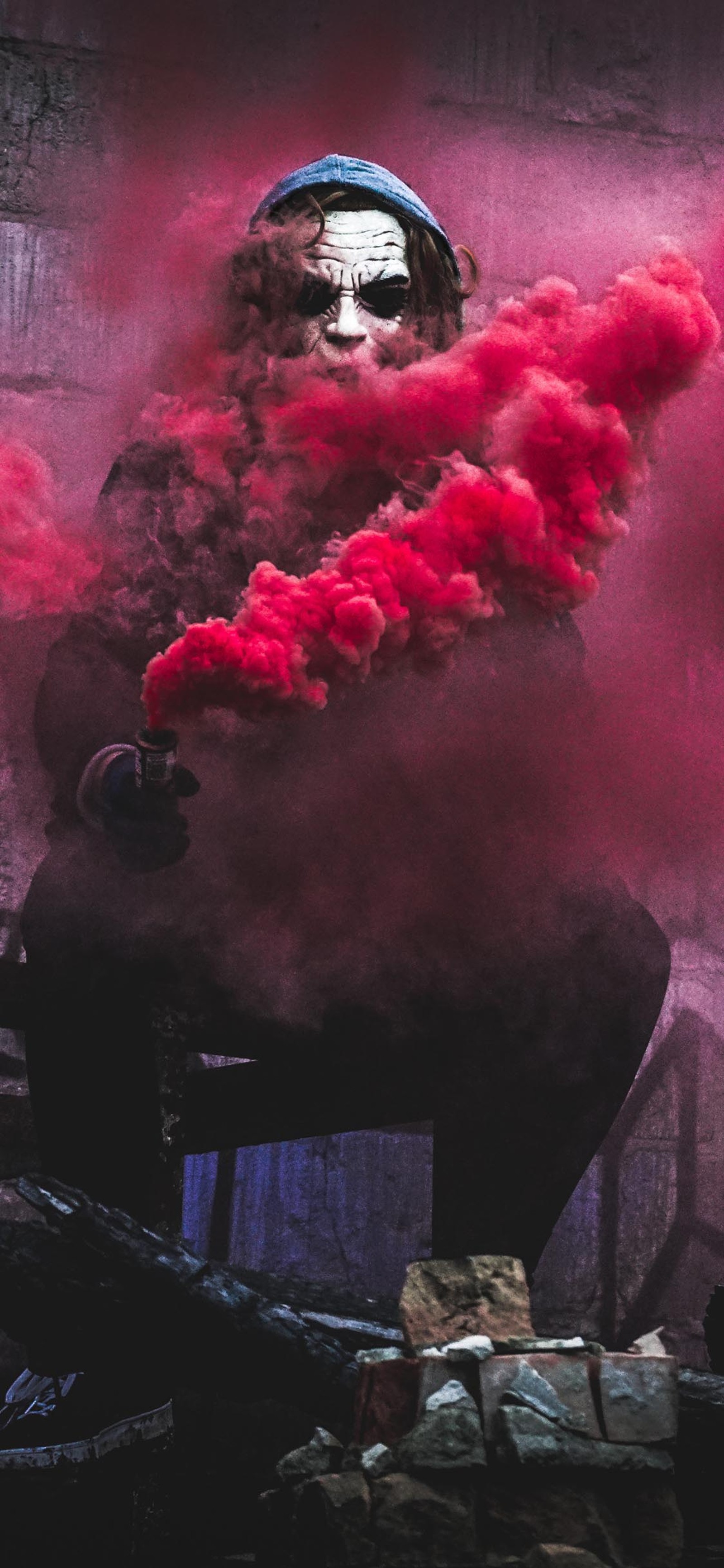 Un homme assis sur une chaise avec de la fumée rouge (danger, sombre, ciel, joker, pouvoir)