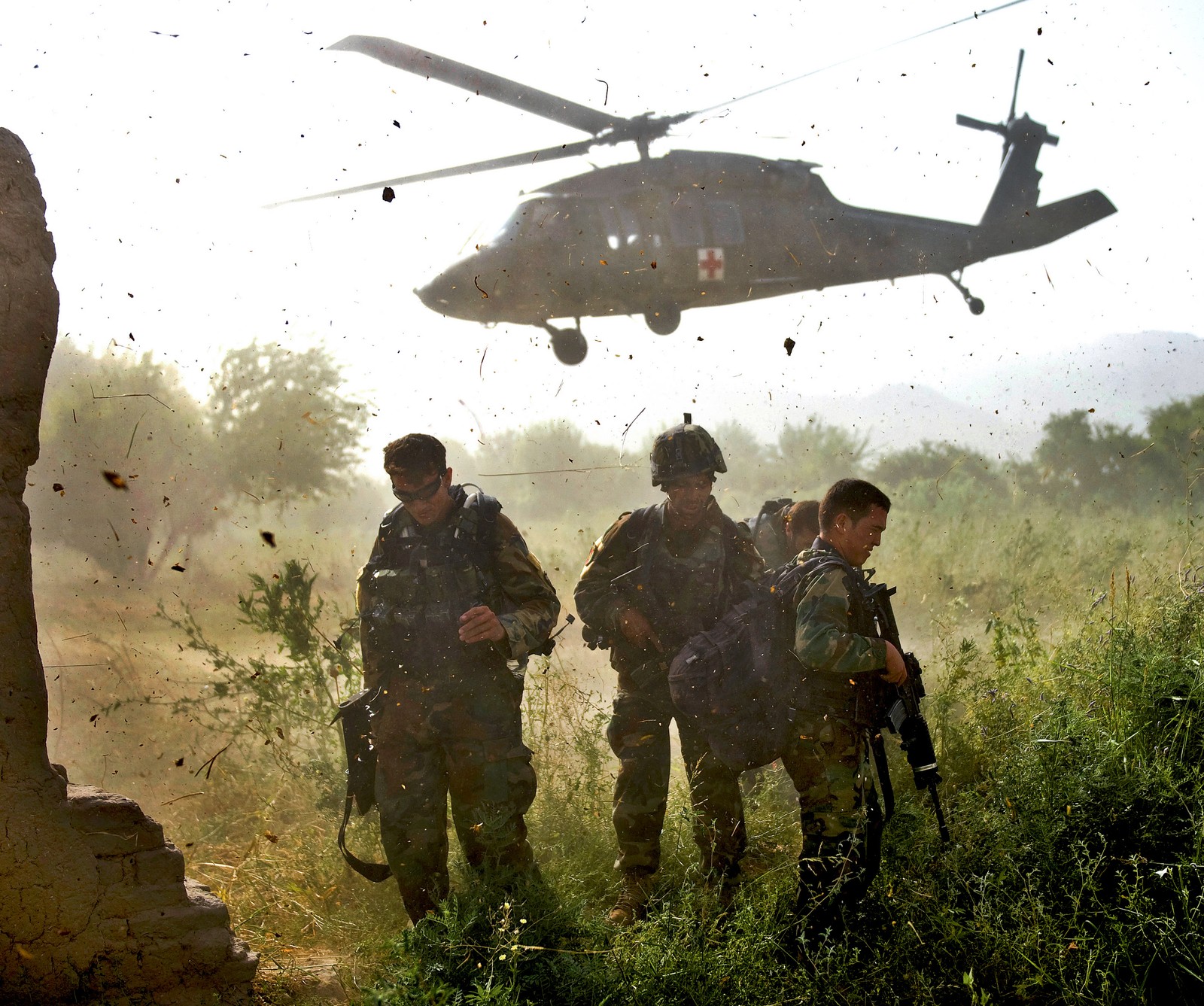 Soldaten stehen auf einem feld mit einem hubschrauber, der darüber fliegt (afghanistan, armee)