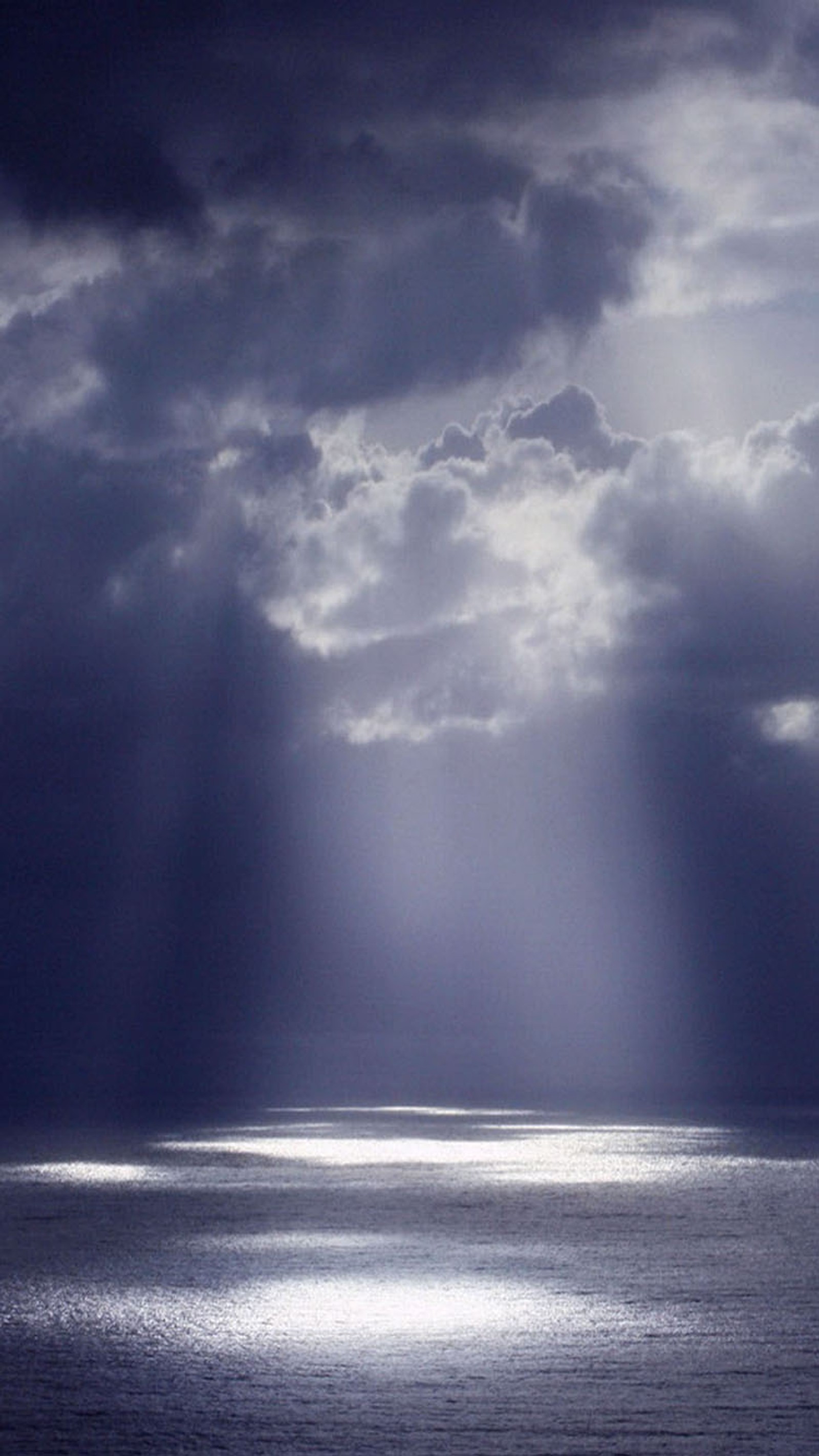 Un bateau dans l'océan sous un ciel nuageux (rayons, soleil)