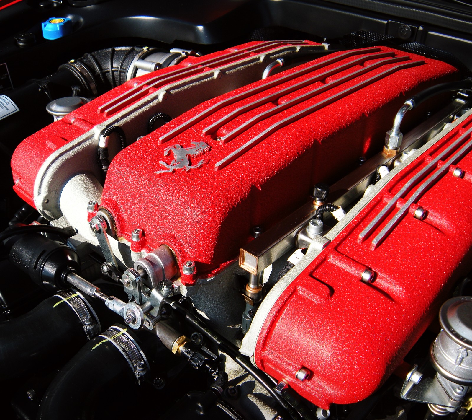 There is a red engine cover on a car engine (auto, car, engine, ferrari, motor)