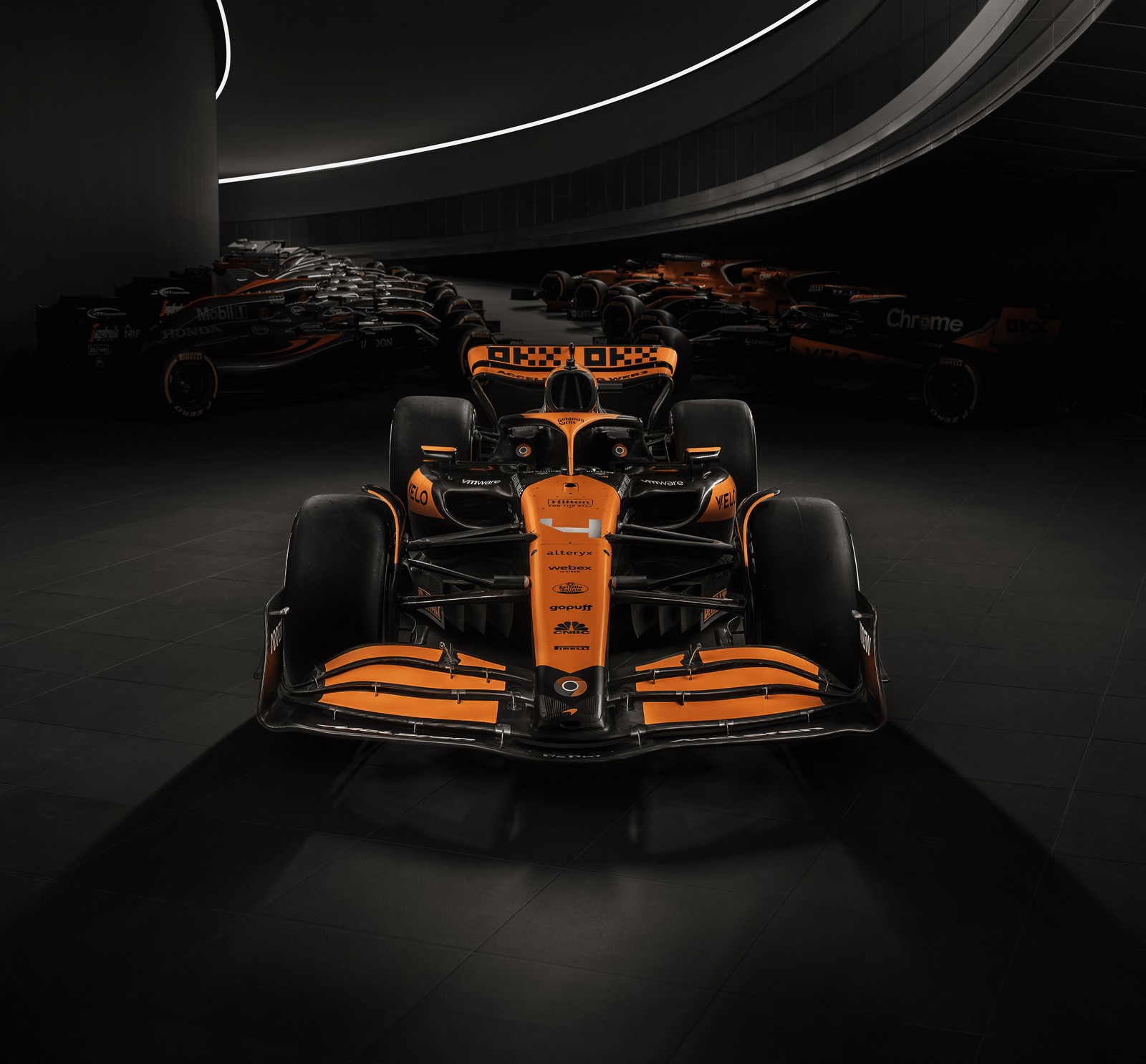 Крупный план гоночного автомобиля в темной комнате (mclaren mcl38, f1 автомобили, тёмный фон, 2024, автомобили формулы 1)