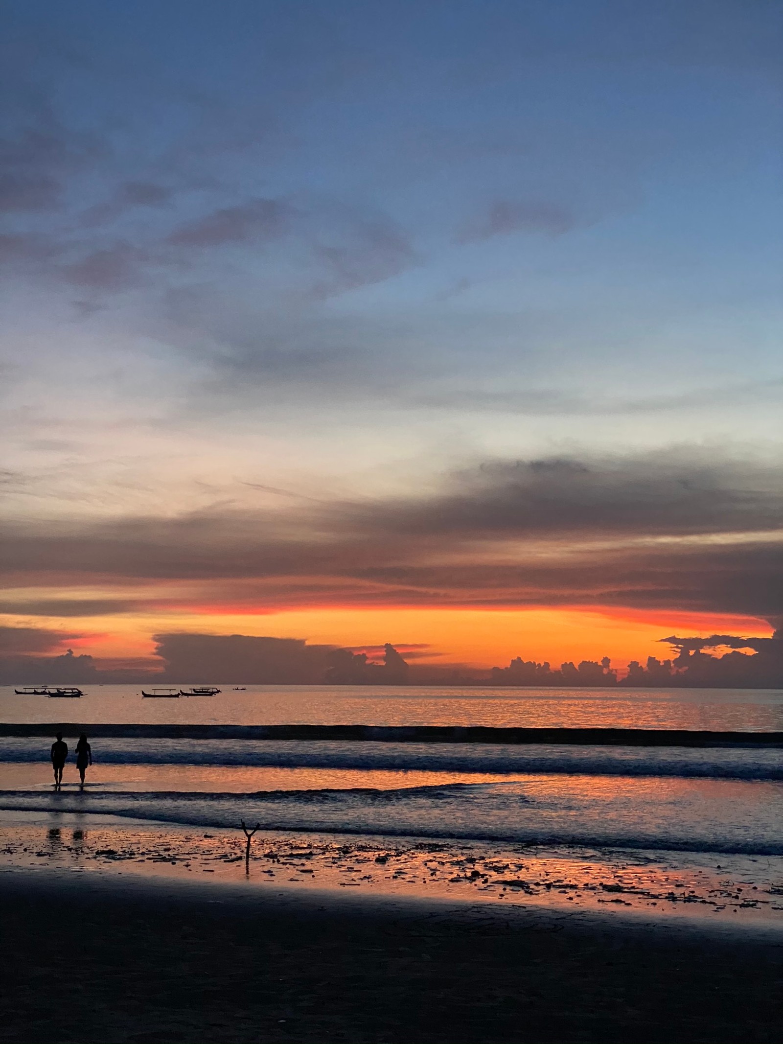 Surfistas caminhando na praia ao pôr do sol com um céu colorido (água, por do sol, luz solar, corpo de água, líquido)