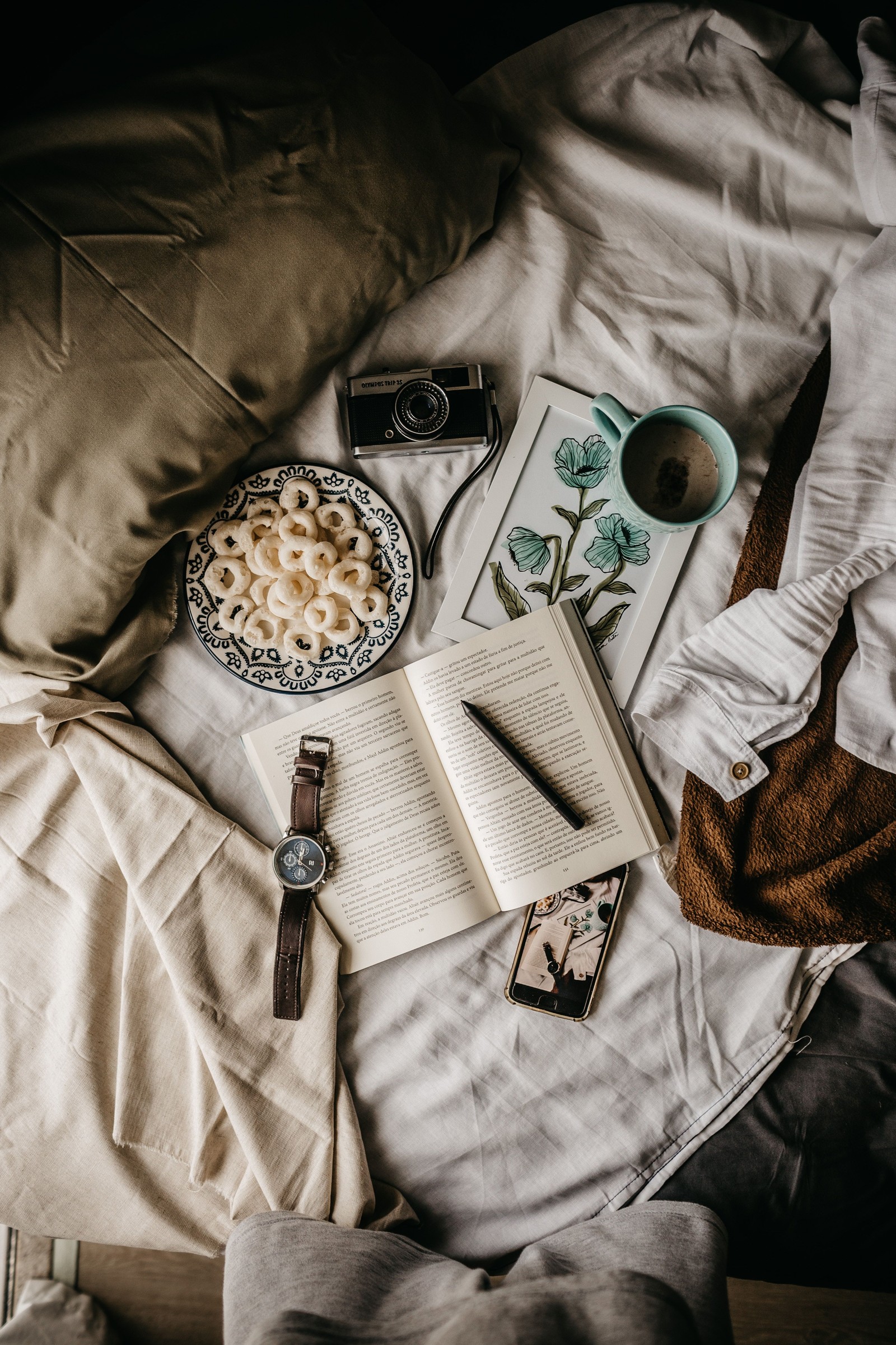 Es gibt ein buch, eine tasse kaffee und einen stift auf einem bett (kamera, textilien, stil)