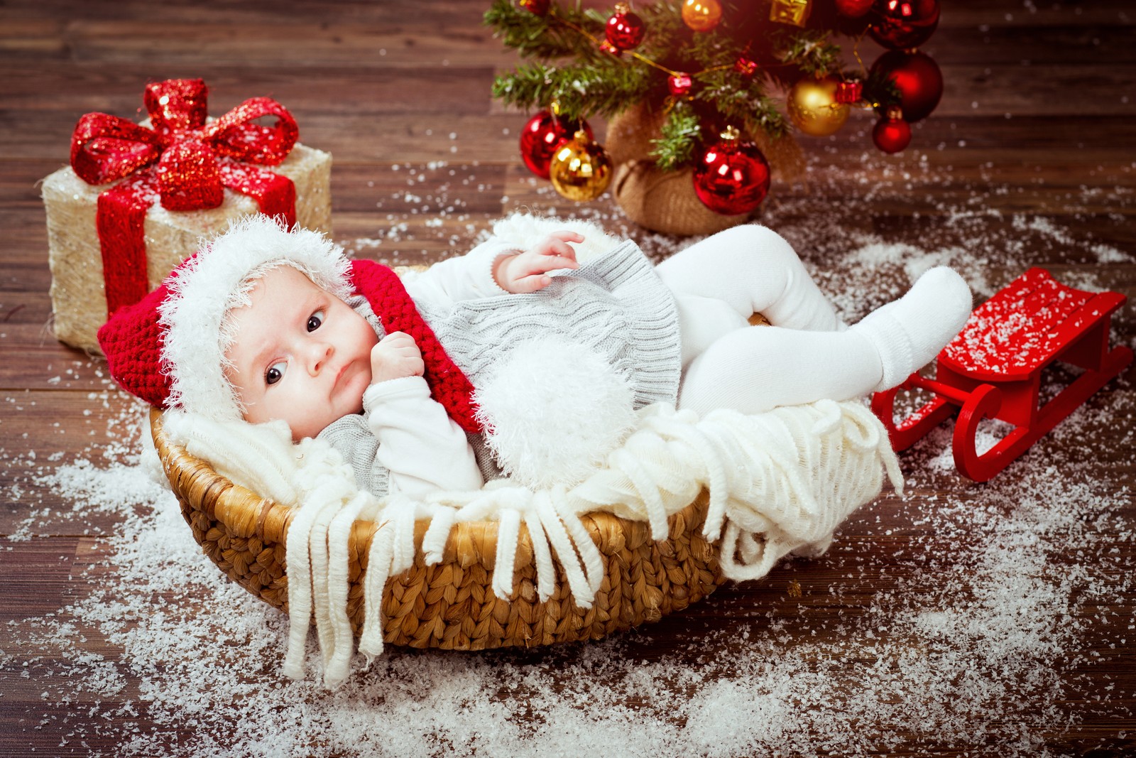 Gros plan d'un bébé portant un bonnet de noël allongé dans un panier (nourrisson, cadeau, noël, décoration de noël, enfant)