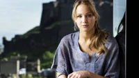 Elegant portrait of a blonde actress with long hair, showcasing her beauty against a scenic backdrop.