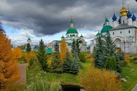 Sérénité d'Automne : Un Monastère Entouré d'Arbres Persistants et de Cieux Dramatiques