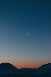 Ciel tranquille du crépuscule avec des traînées de condensation au-dessus de l'horizon montagneux