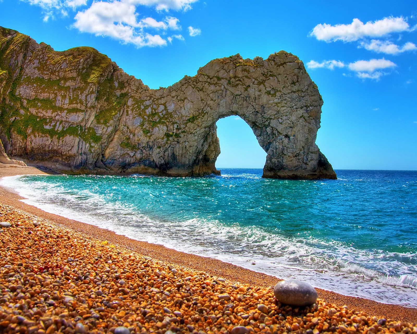 Une arche arabe dans la formation rocheuse sur la plage près de l'océan (plage, roche, mer, pierres)