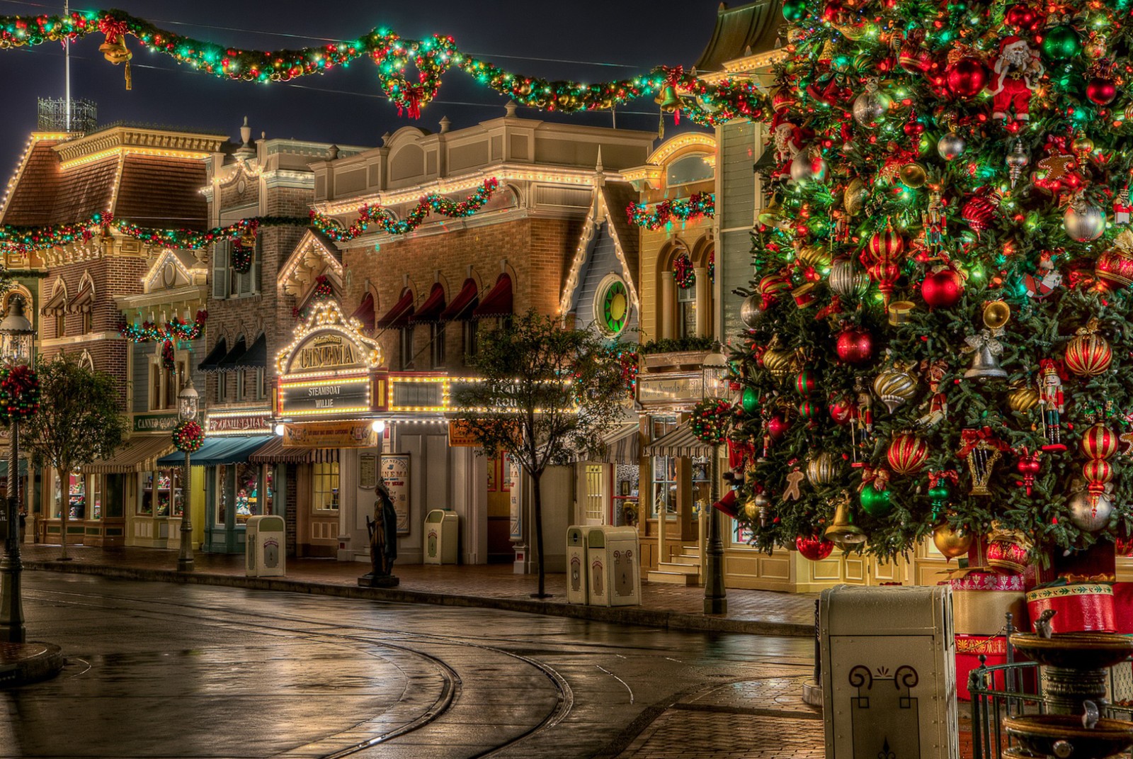 Um close de uma árvore de natal em frente a um prédio (natal, cidade, disney, luz, estrada)