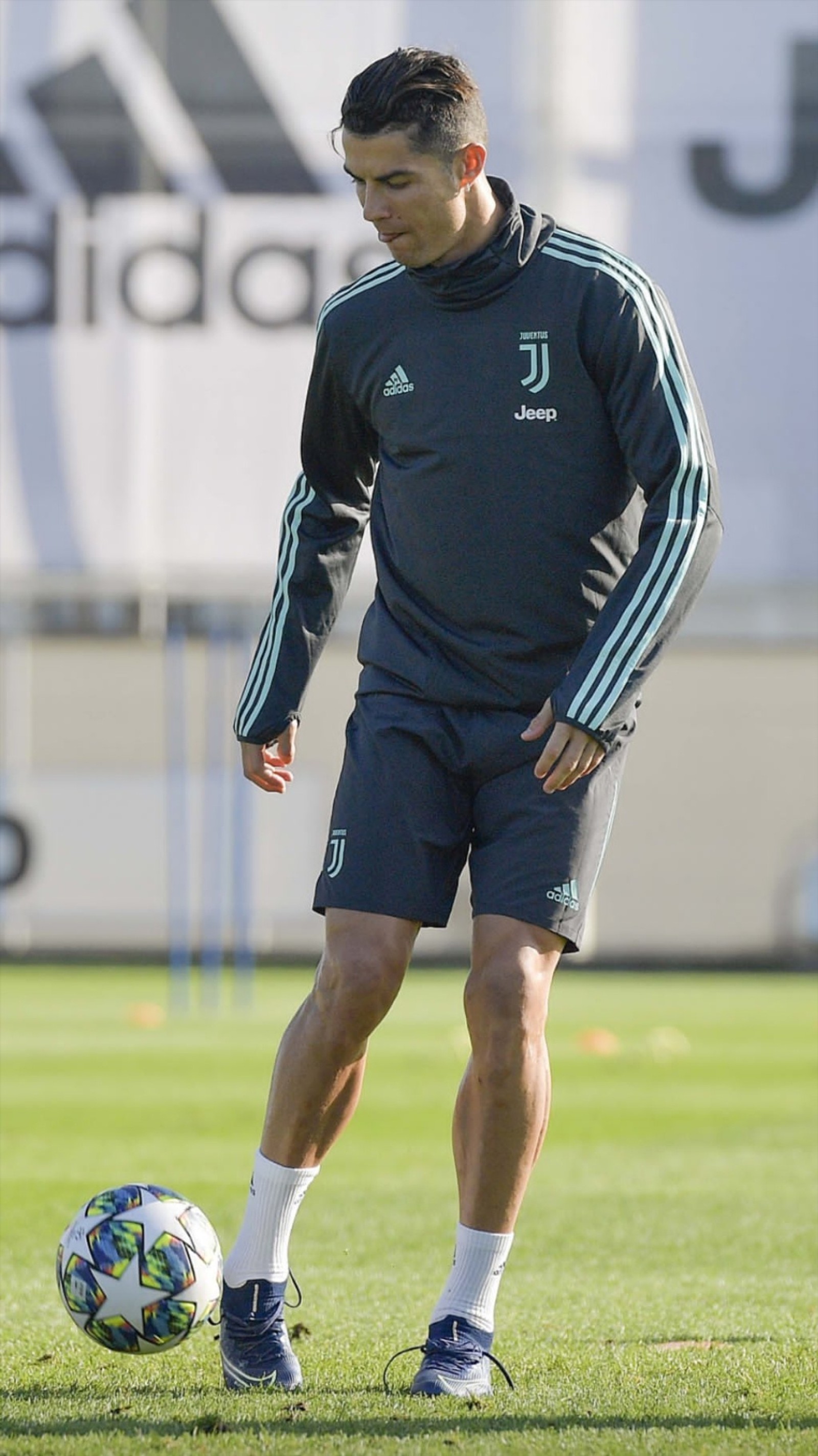 Un hombre árabe con una camisa negra y pantalones cortos jugando con un balón de fútbol (cristiano, fútbol, juventus, leyenda, ronaldo)