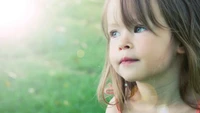 A thoughtful young girl with delicate features and soft hair gazes into the distance, evoking a sense of innocence and contemplation amidst a dreamy background.