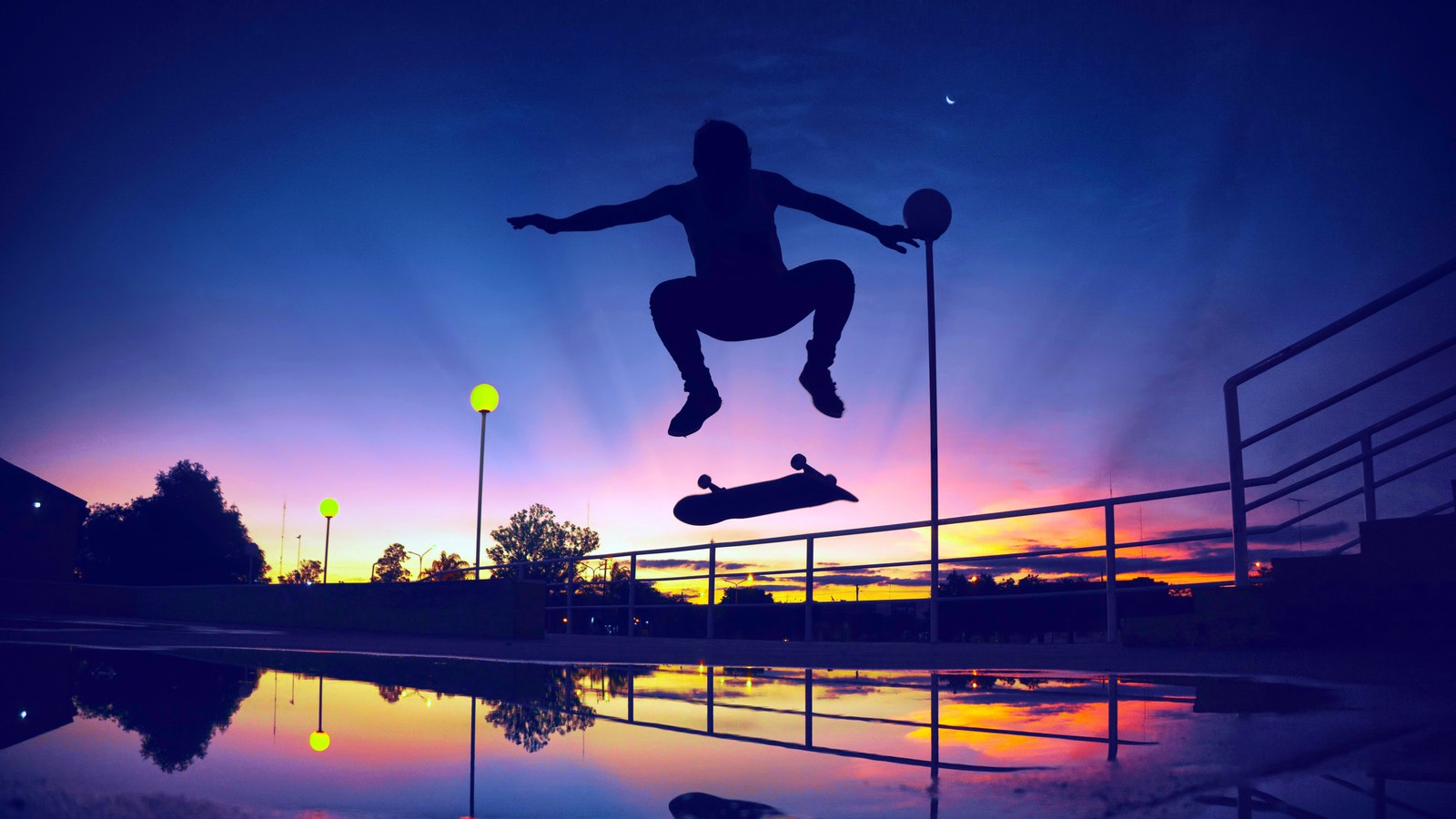 Un skateur sautant par-dessus une flaque d'eau au coucher du soleil (patinage, silhouette, coucher de soleil, paysage)