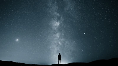 Silhouette of a man under a starry night sky with the Milky Way.