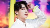 Jungkook von BTS in einer stilvollen Pose vor einem lebhaften Hintergrund.