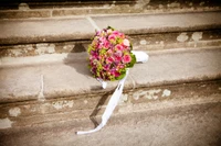 Elegant pink flower bouquet resting on stone steps, perfect for weddings and special occasions.