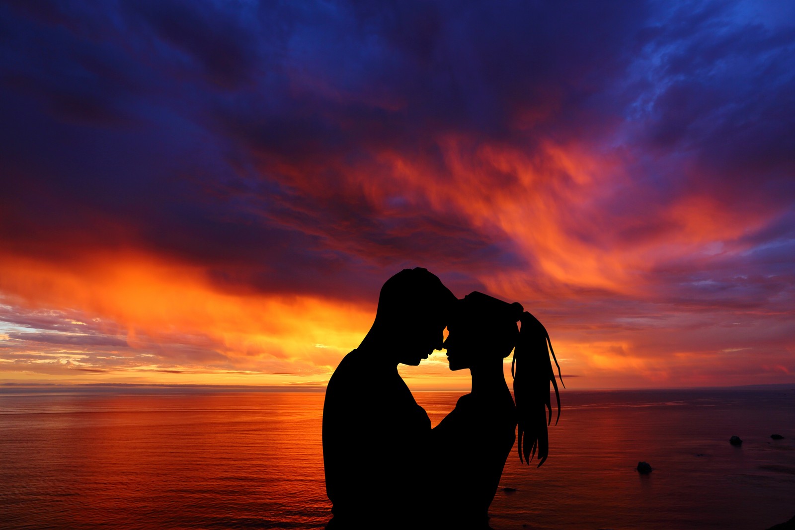 Silhouette d'un homme et d'une femme s'embrassant au coucher du soleil sur la plage (couple, romantique, silhouette, coucher de soleil, paysage marin)