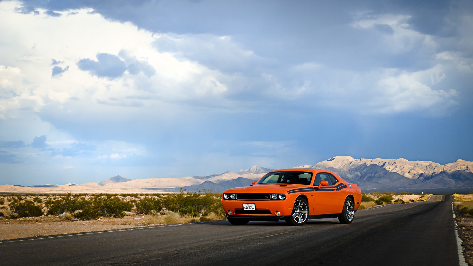 Une voiture orange arabe circulant sur une route dans le désert (dodge, voiture, voiture de sport, route, voyage sur la route)