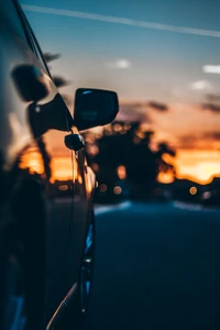 Reflexiones de la tarde: Una silueta de coche contra un cielo de atardecer colorido