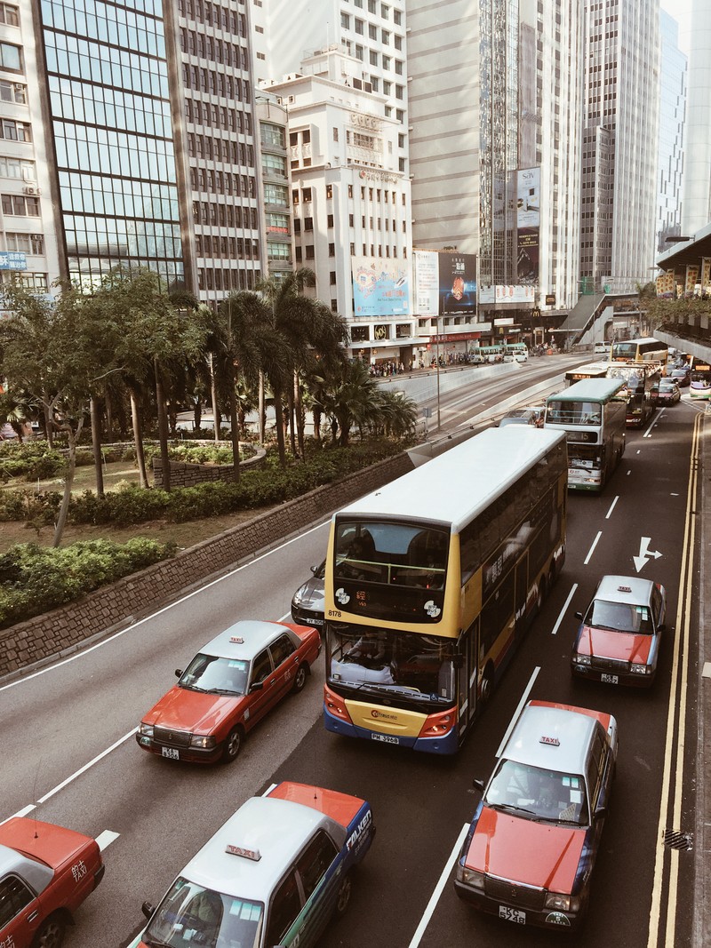 Автомобили и автобусы едут по оживленной городской улице (гонконг, hong kong, король, транспорт, башенный блок)