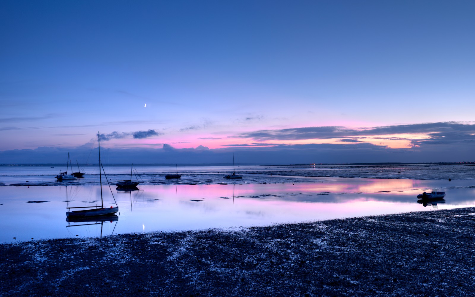 Há barcos na margem de um lago calmo ao pôr do sol (praia, cenário, por do sol, reflexo, nuvens)