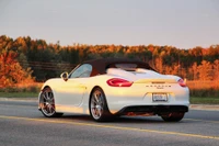 Eleganter weißer Porsche Cayman Cabriolet auf malerischer Straße bei Sonnenuntergang