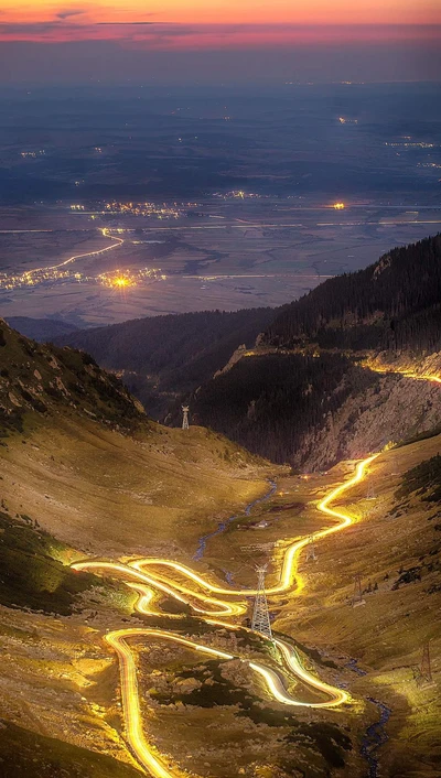 Estrada sinuosa através de uma paisagem montanhosa ao anoitecer