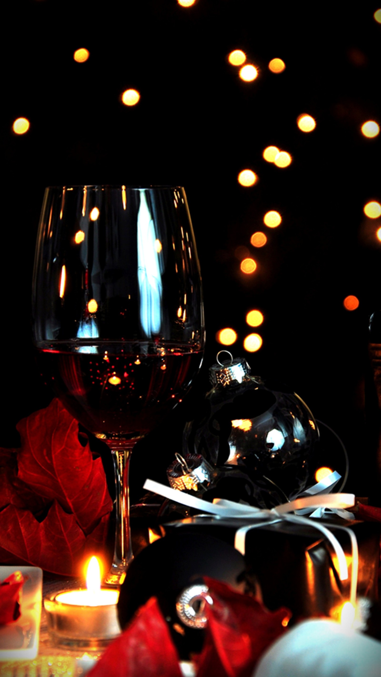 Il y a un verre de vin et une bougie sur la table. (balles, noël, cadeaux)