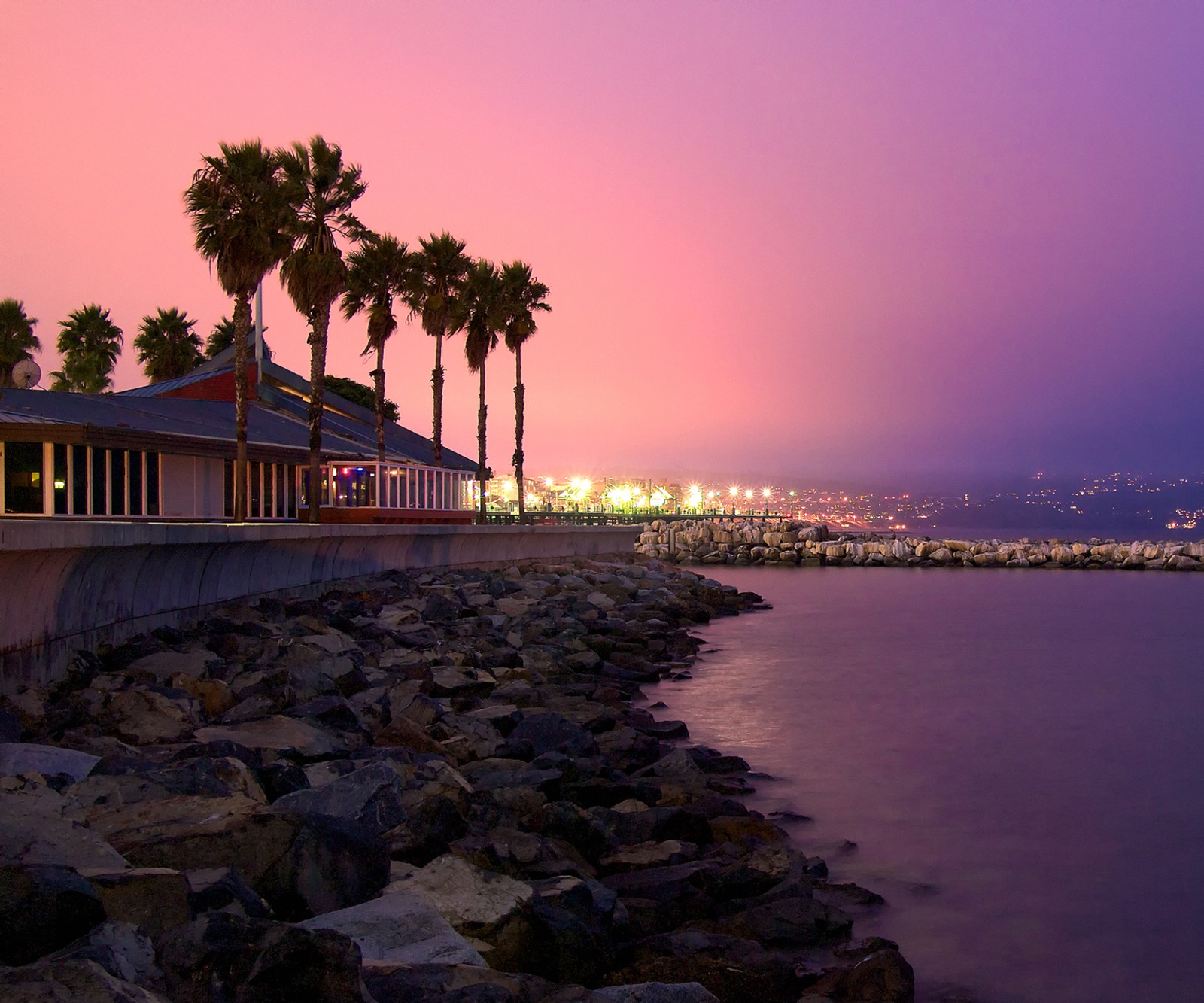 Arafed view of a beach with palm trees and a building (la, sunset)