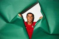 Cristiano Ronaldo playfully breaks through a green backdrop, showcasing his vibrant personality and enthusiasm for football.