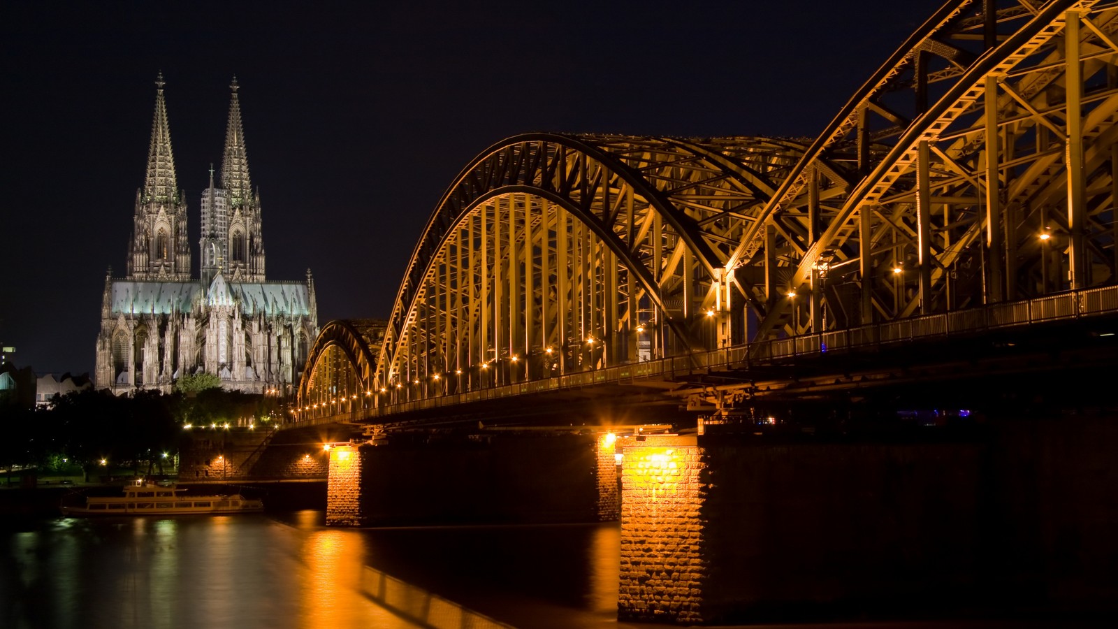 Un puente arqueado sobre el río con una catedral de fondo (puente, noche, hito, reflexión, arquitectura)