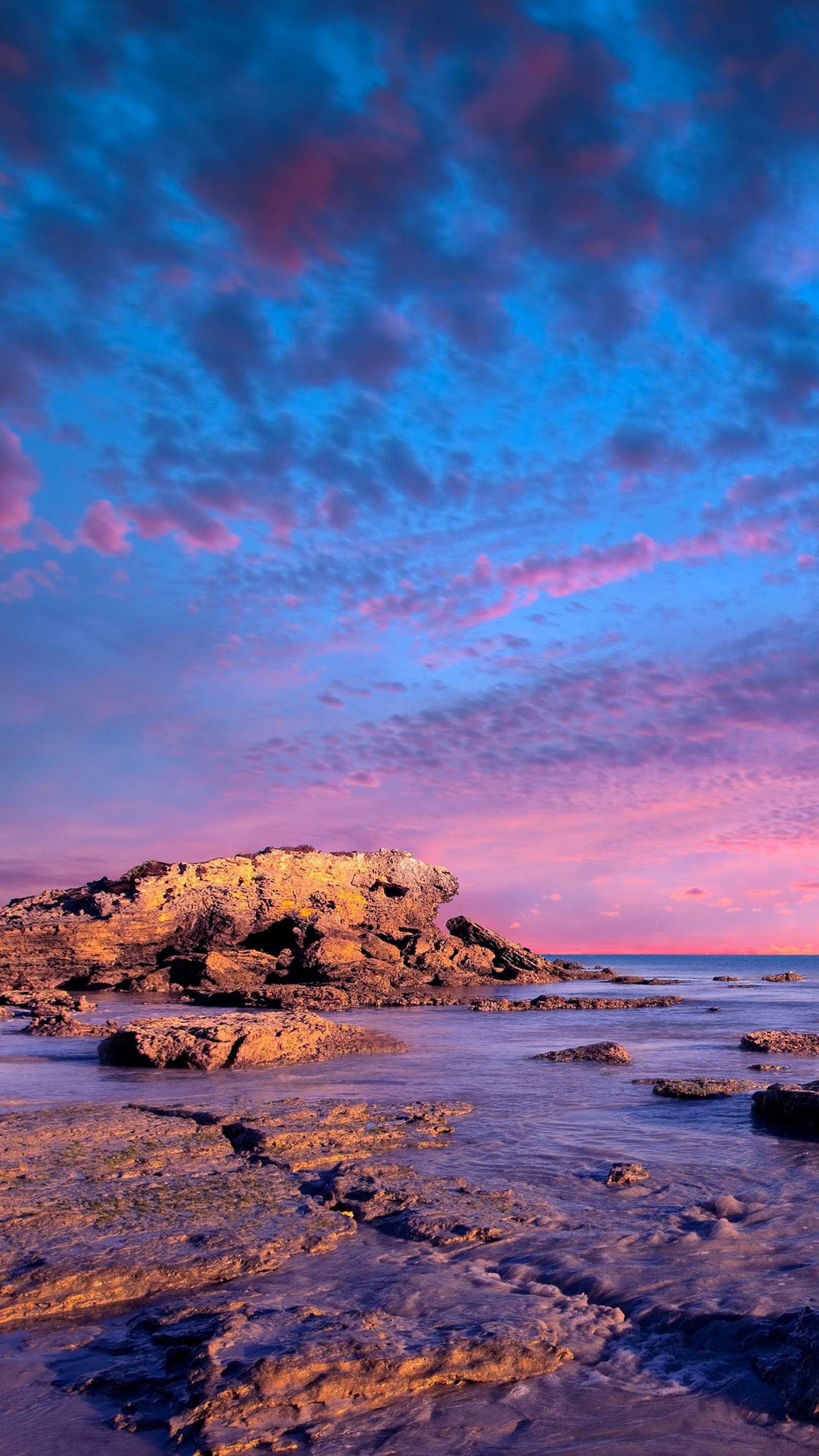 Céu roxo e azul com nuvens sobre uma praia rochosa (nuvem, água, atmosfera, azul, paisagem natural)