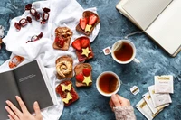 Gemütliches Brunch-Setup mit künstlerischen Toasts, Tee und einem Buch