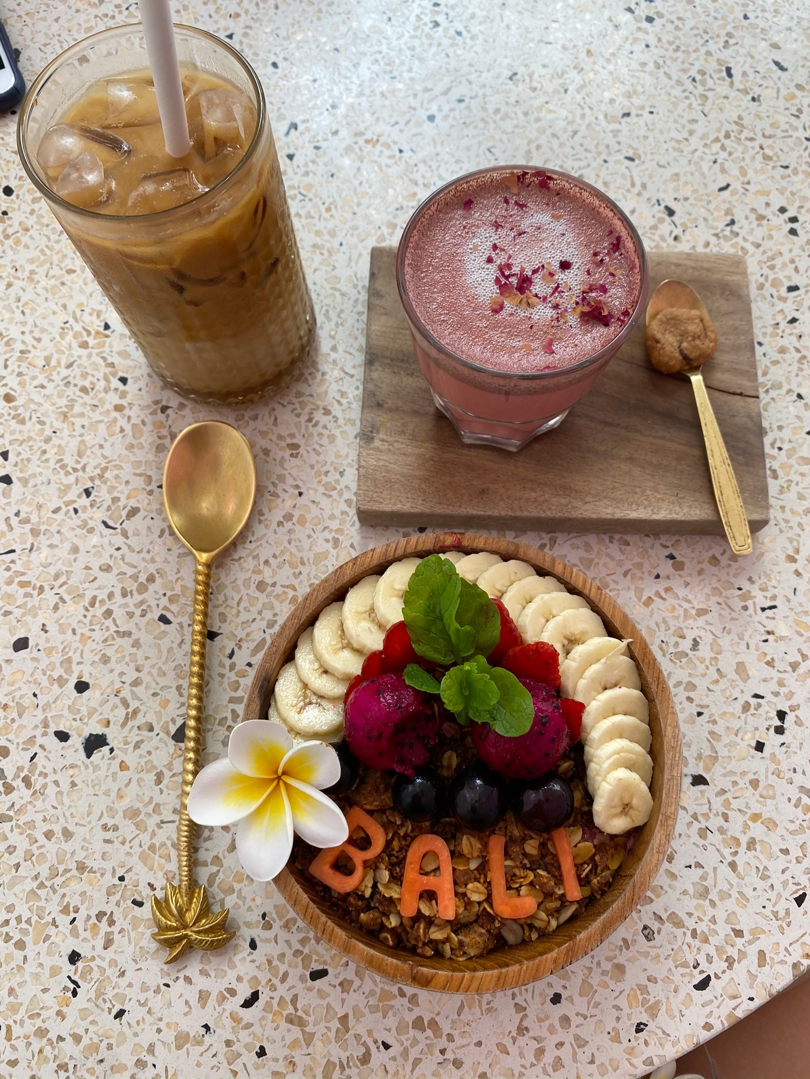 Há uma tigela de frutas e uma bebida em uma mesa. (bali, superalimento, café da manhã, smoothie, sobremesa congelada)