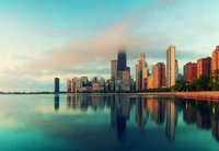 Die Skyline von Chicago, reflektiert in ruhigen Gewässern unter einem nebligen Horizont