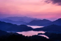 Chaîne de montagnes sereine au coucher du soleil avec des lacs tranquilles et un ciel rose