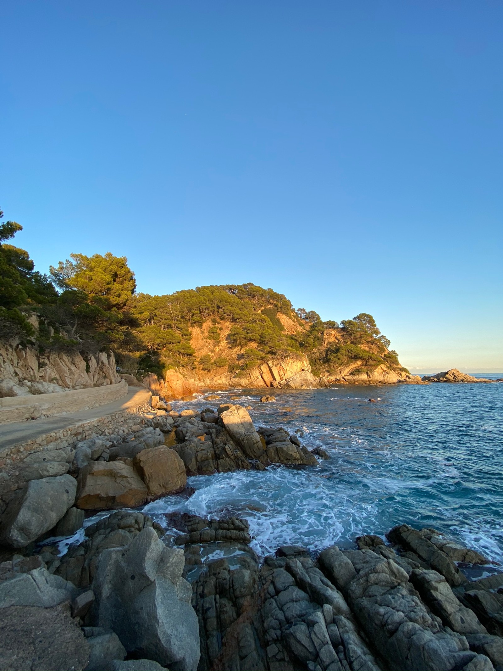 There is a beach with rocks and a body of water (coast, water, promontory, science, physics)