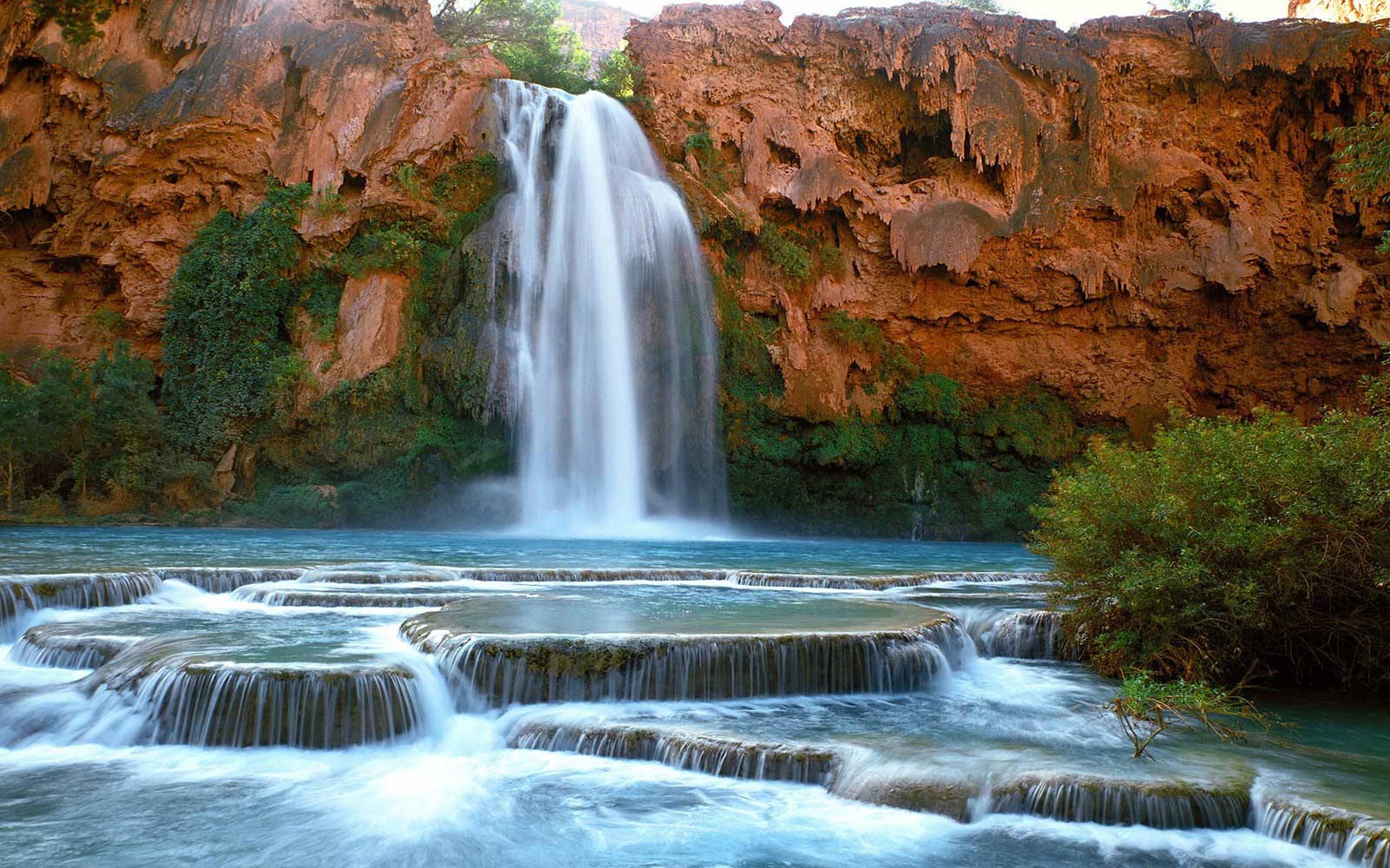 A waterfall in the middle of a canyon with a few rocks (supai, grand canyon, waterfall, navajo falls, water resources)