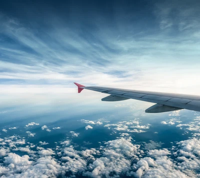 Amplio cielo azul con ala de avión y nubes esponjosas