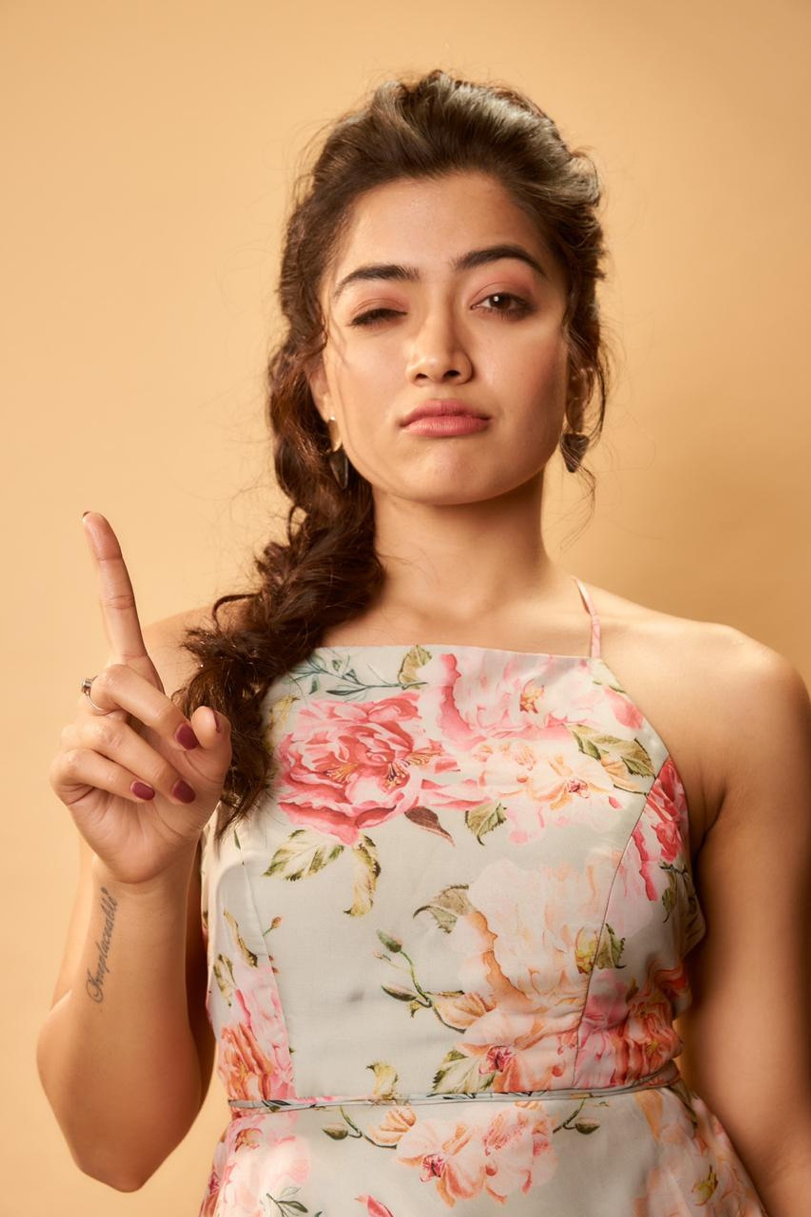 Gros plan d'une femme en robe à fleurs faisant un signe de paix (mandanna, rashmika)