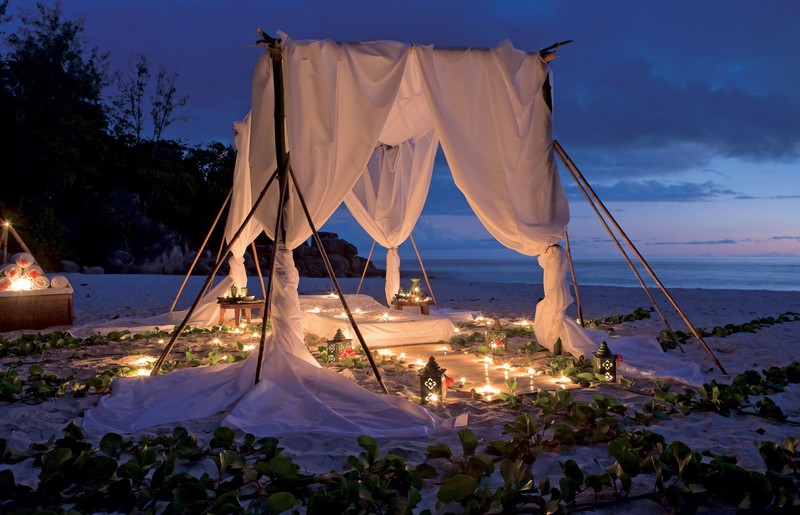 Candles are lit on a bed on the beach at night (romance, vacation, sea, evening, tent)