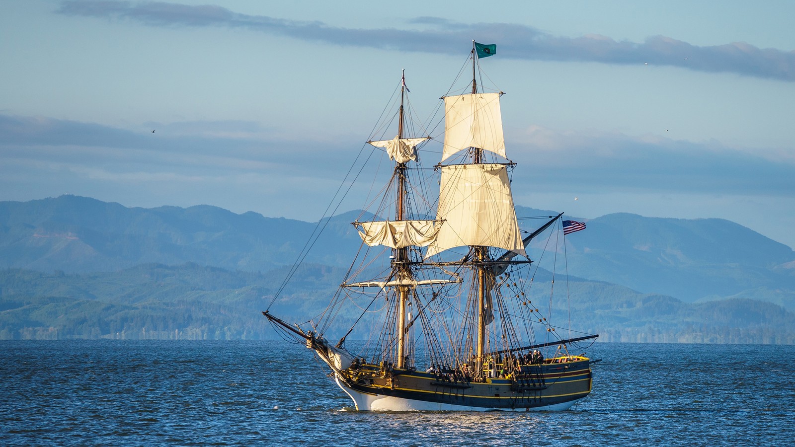 Un voilier dans l'océan avec des montagnes en arrière-plan (grand navire, voilier, barquentine, navire amiral, bateau)