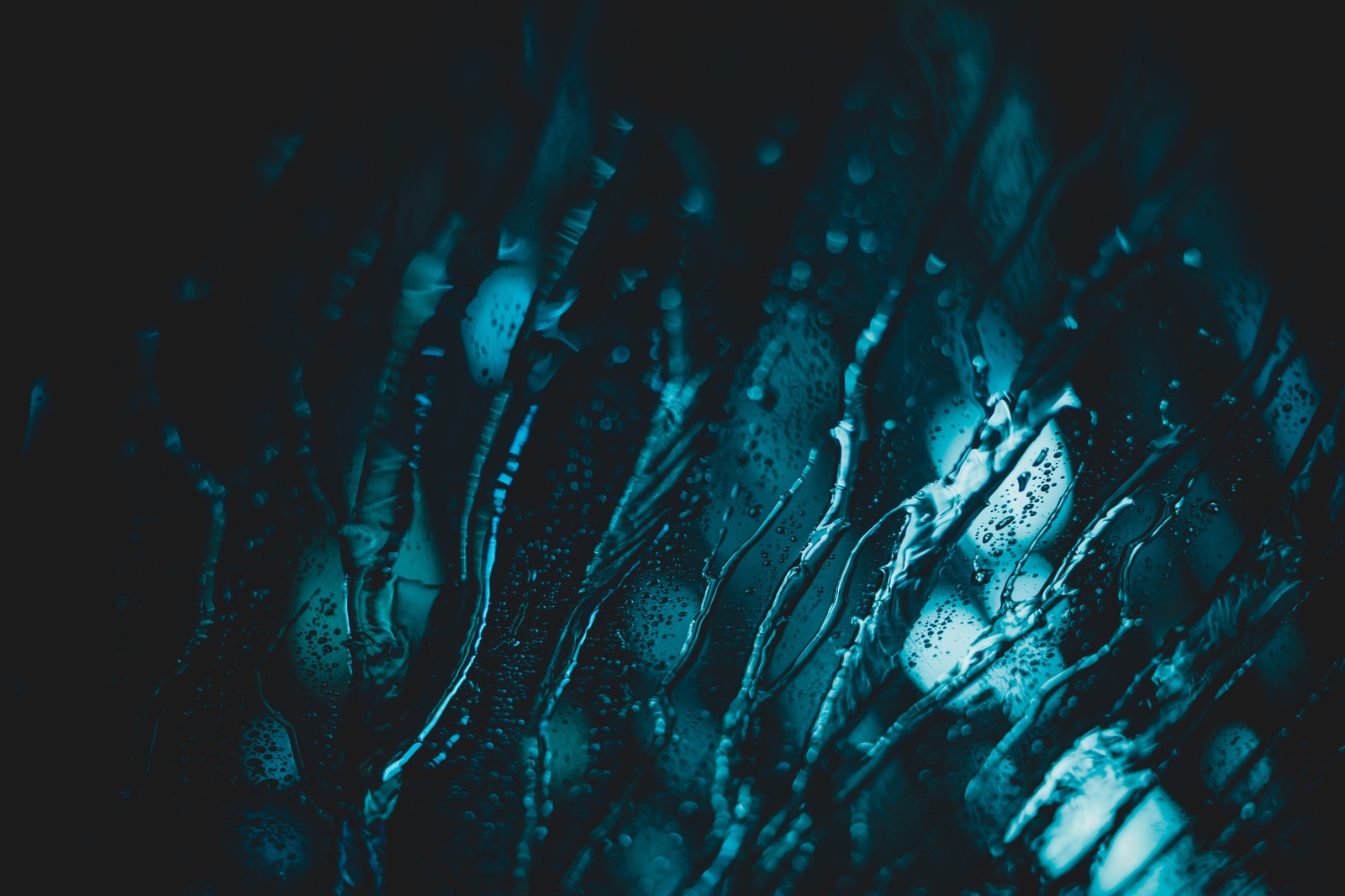 A close up of a bunch of water droplets on a glass (blue, water, black, green, turquoise)