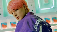 Jeno of NCT Dream in a vibrant, retro-themed setting with pastel colors and a striking pink hairstyle.