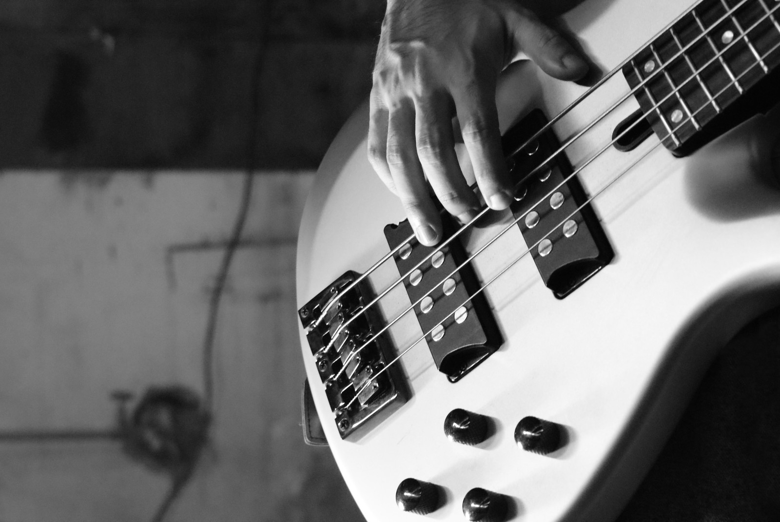 Someone is playing a bass guitar in a black and white photo (bass guitar, guitar, double bass, electric guitar, string instrument)