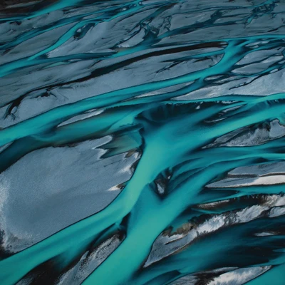 Une vue aérienne époustouflante d'une rivière tressée dans le parc national Aoraki Mount Cook, Nouvelle-Zélande, mettant en valeur des ruisseaux turquoise vibrants serpentant à travers les forts contrastes du paysage des Alpes du Sud.