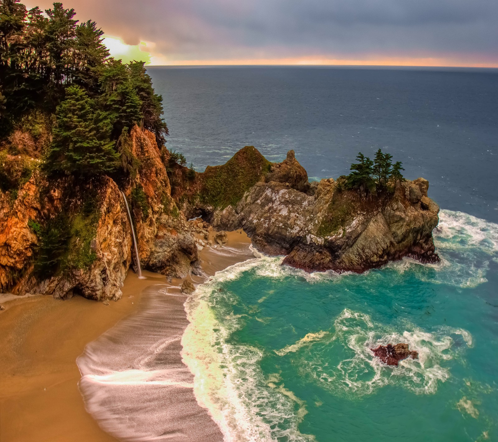 Vista de uma praia com uma cachoeira e um corpo d'água (alcove, praia, oceano, areia, mar)