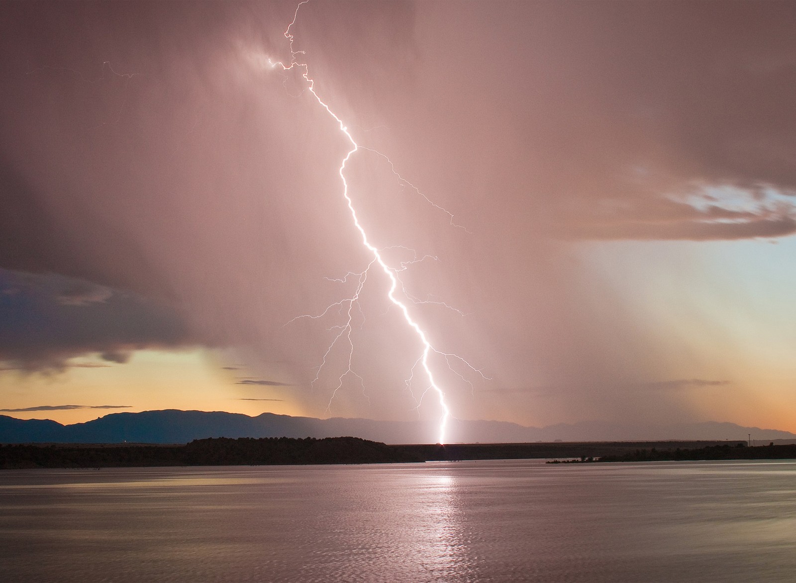 Relâmpagos arafed cruzando o céu sobre um lago (iluminação, oceano, água)