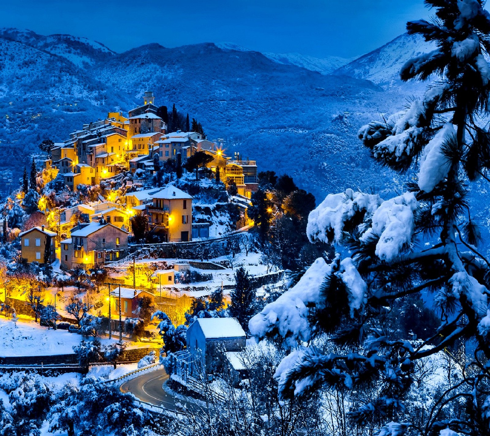 Una vista de un pueblo en las montañas cubierto de nieve (invierno)