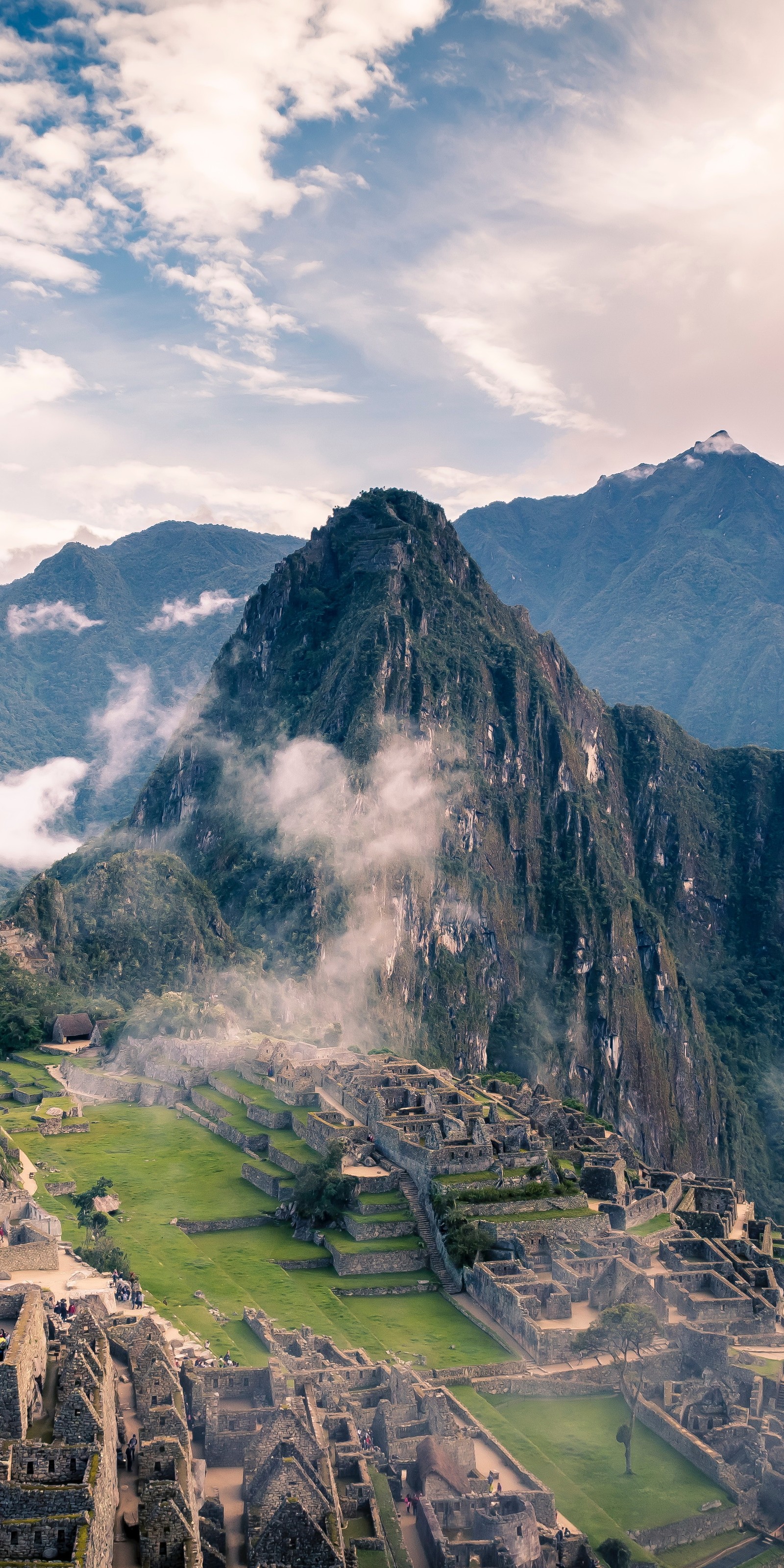 Montagnes au loin avec quelques bâtiments et quelques personnes. (machu picchu, empire inca, voyage, tourisme, randonnée)